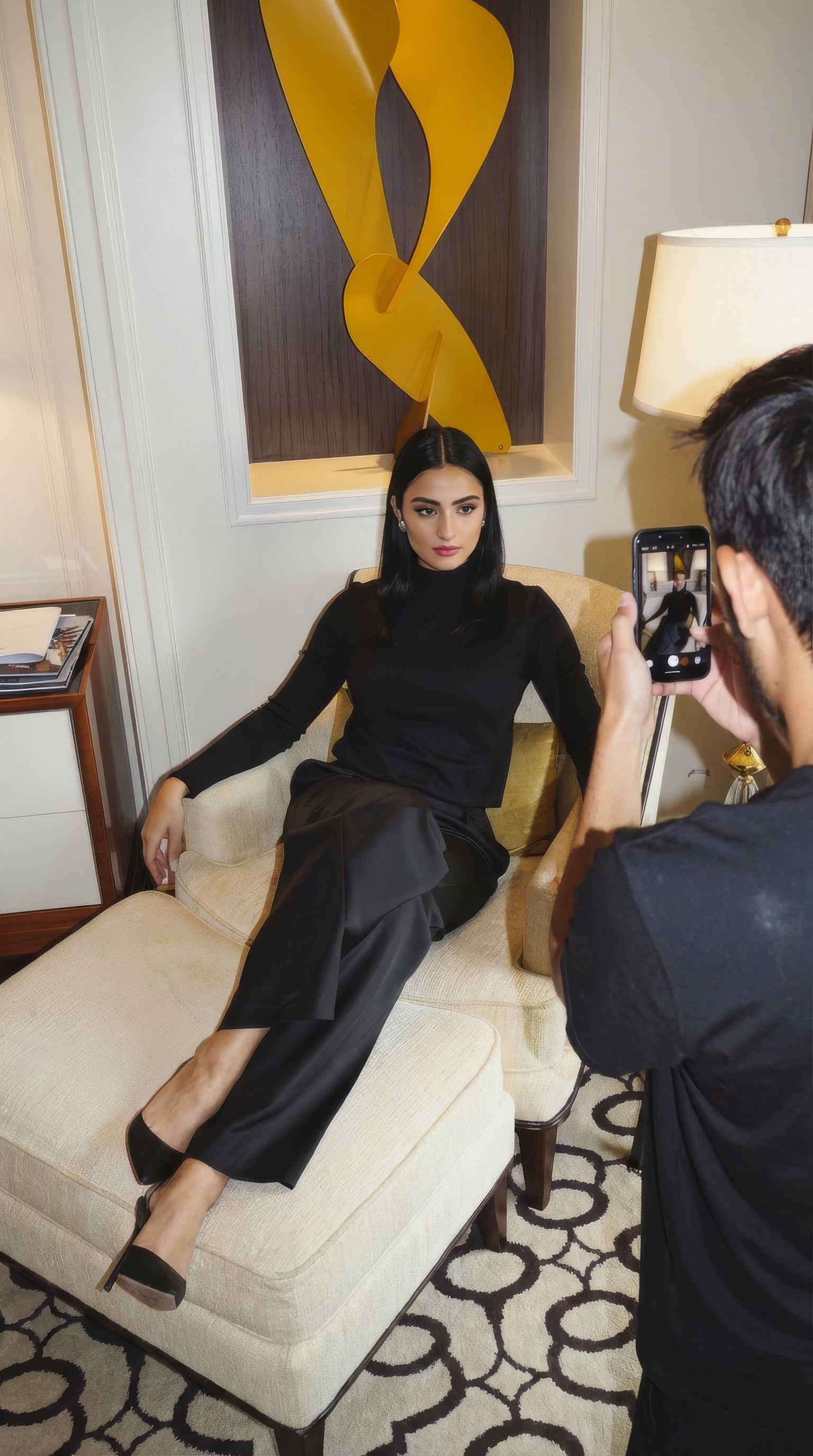 Creator being photographed on a sofa by someone holding a phone