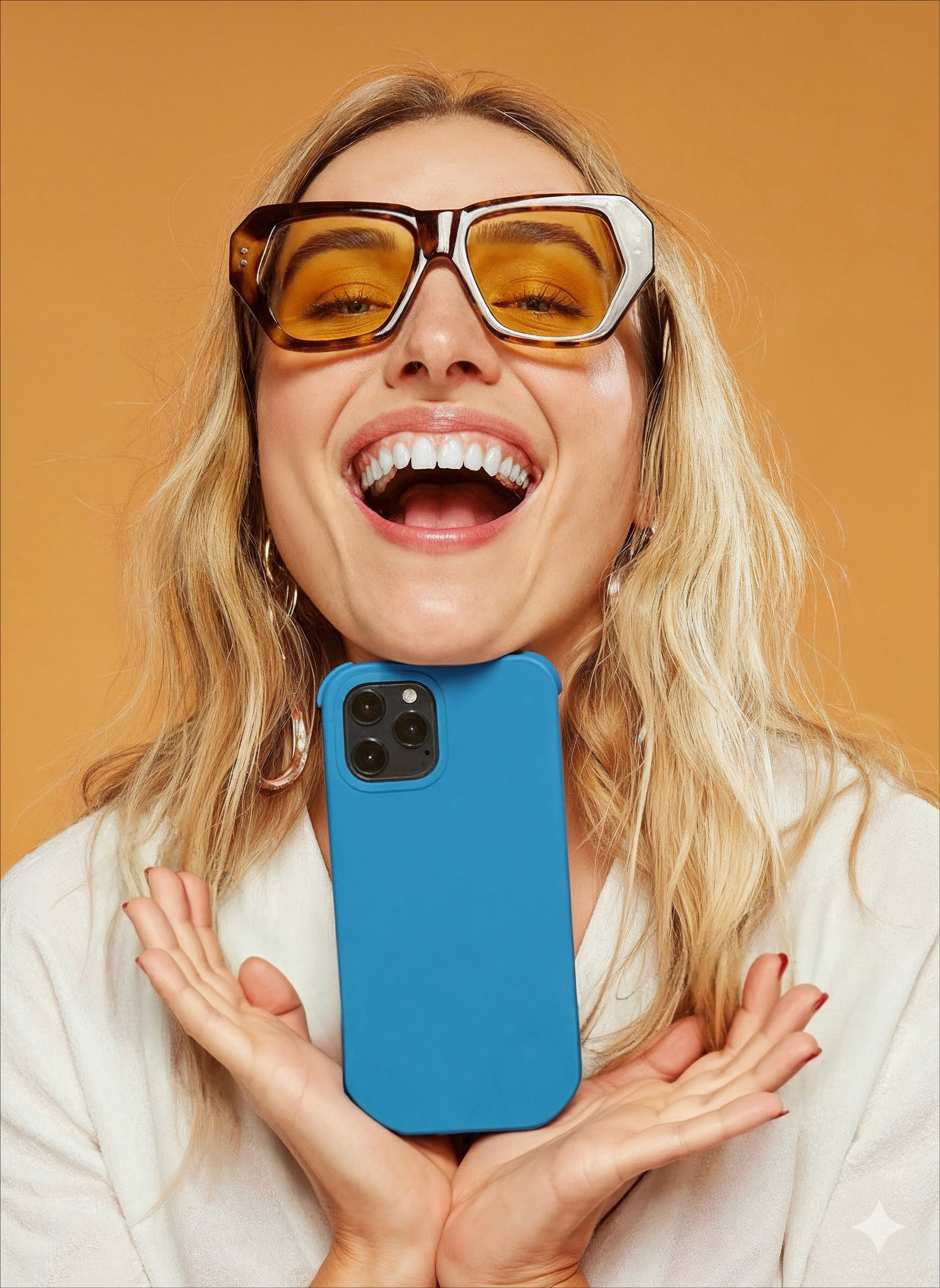 Laughing creator in yellow sunglasses holding up a blue phone case