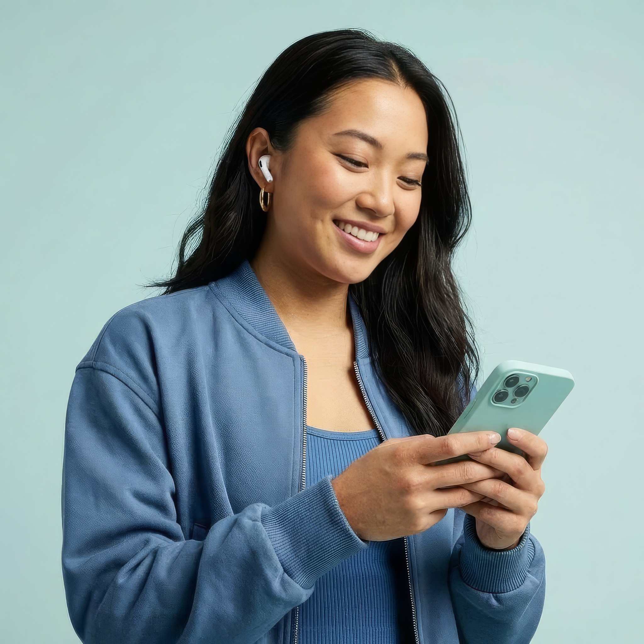 Creator wearing earbuds, smiling at her phone